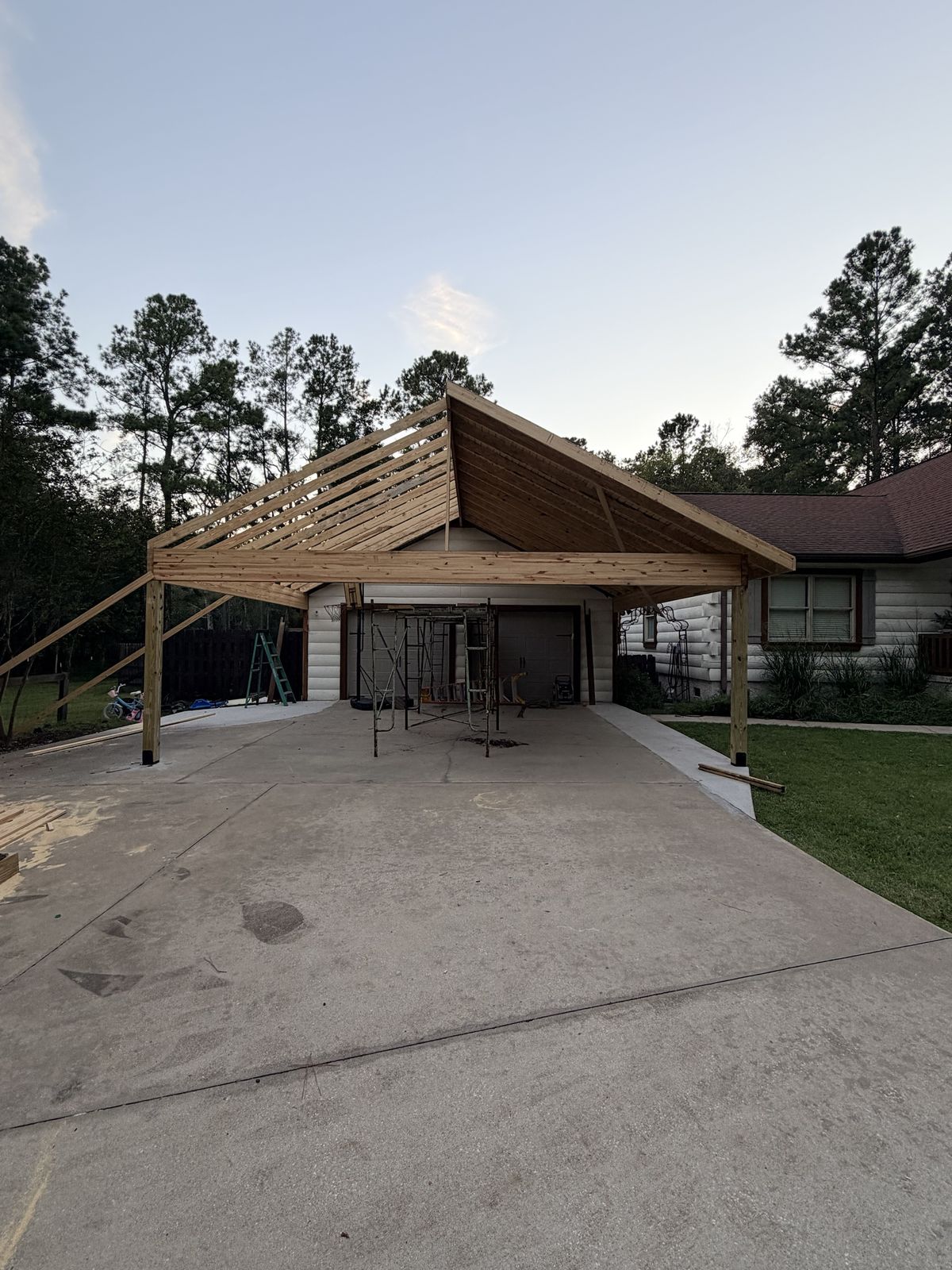 Carport addition, framing. Roof framing going up over the driveway.