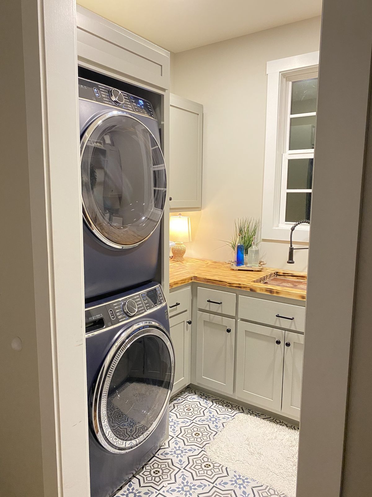 Laundry room. Stacked washer and dryer built into the cabinetry, with a utility sink.