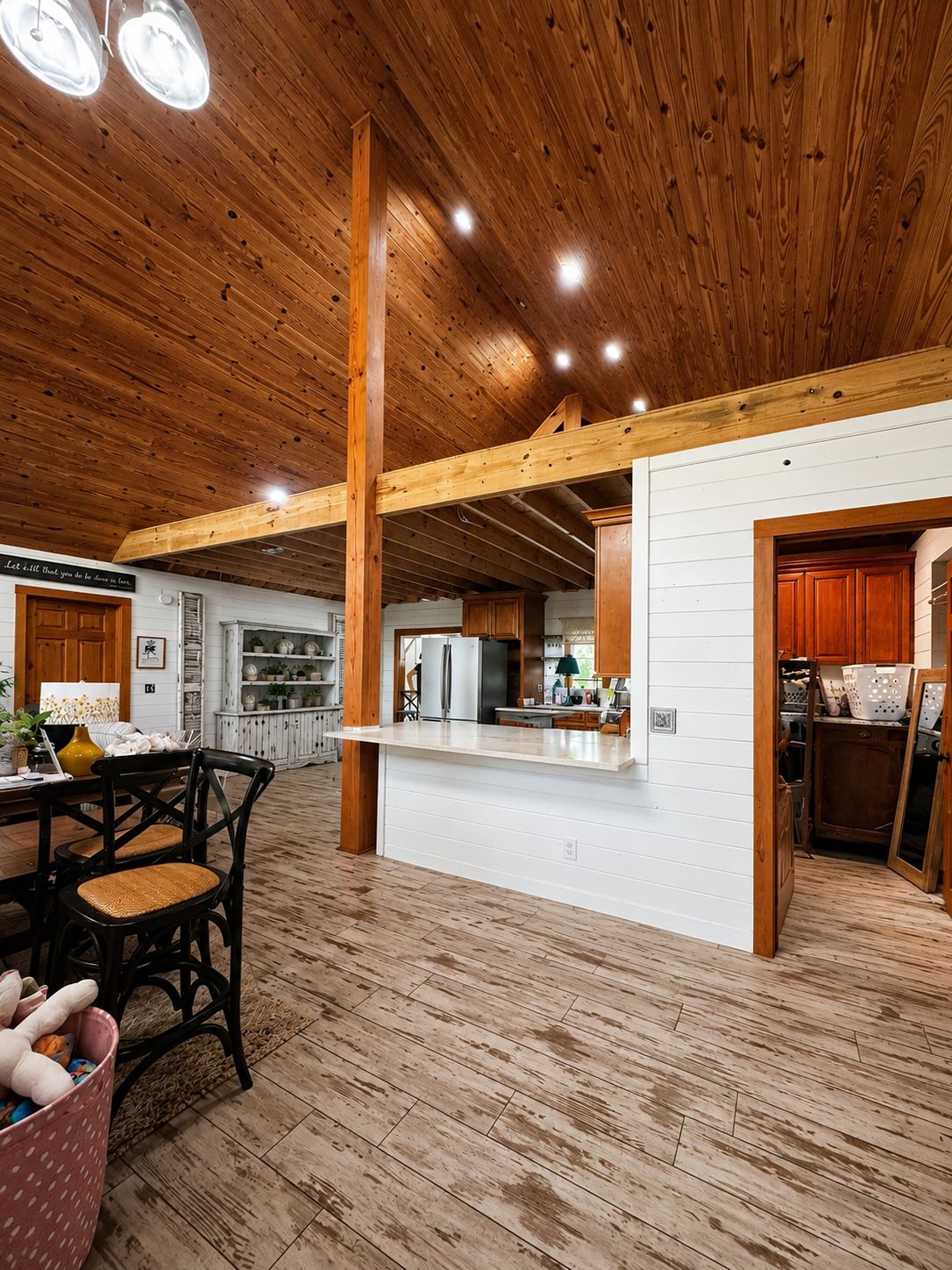 Open living area. Vaulted wood ceiling, exposed beams, and shiplap walls.